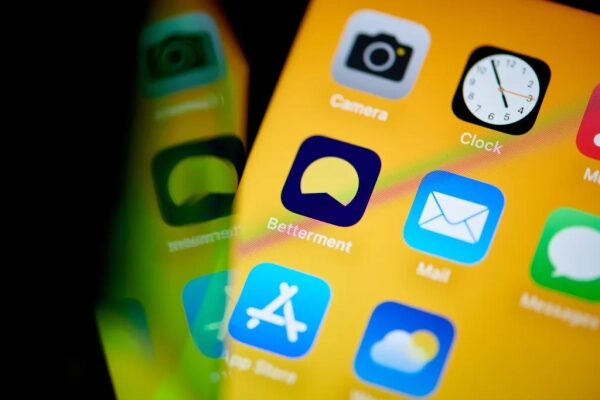 Иконки приложений на экране смартфона с желтым фоном.