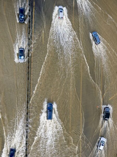 Калифорнийская автомагистраль затоплена из-за прилива. 10 Автомобили едут по затопленной дороге после наводнения, создавая волны на воде.