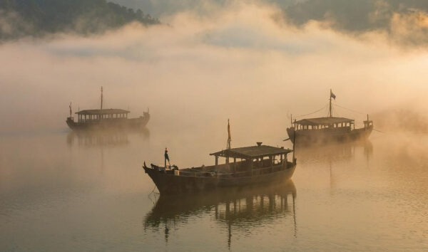 Лодки на туманных водах озера среди утреннего тумана, романтика природы.