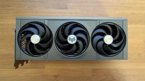 Трехвентиляторная видеокарта на деревянной поверхности, вид сверху.