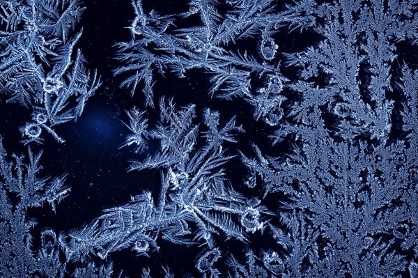 Иней на стекле: узоры зимнего мороза крупным планом.