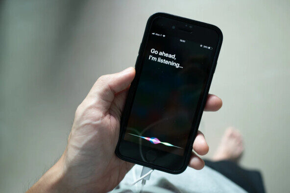 Человек держит iPhone с активированной Siri и текстом "Go ahead, I'm listening".