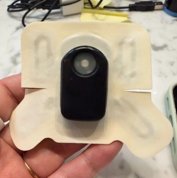 Черный медицинский датчик на клейкой основе в руке. Электронное устройство.