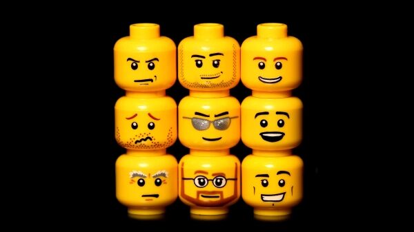 Желтые головы LEGO с разными выражениями лиц на черном фоне.