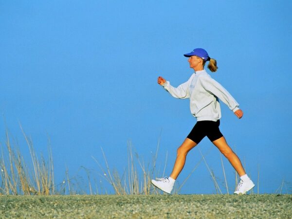 Человек в спортивной одежде идет по тропинке на фоне голубого неба.