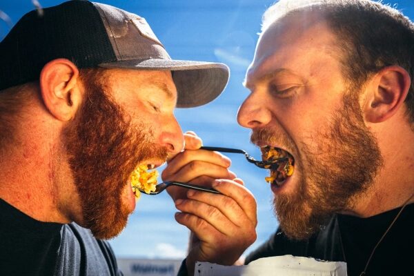 Изображение может содержать: голову Алекса Клэра, лицо человека, одежду взрослого, шляпу, еду и другие предметы.