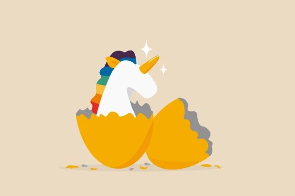Единорог с радужной гривой вылупляется из яйца на бежевом фоне.