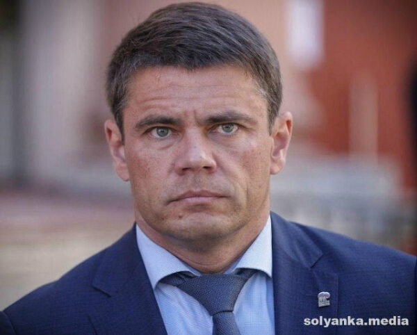 Мужчина в костюме и галстуке на улице, логотип сайта в углу изображения.