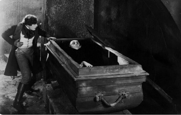 Кадр из немого фильма: вампир в гробу и человек рядом в тревожной сцене.