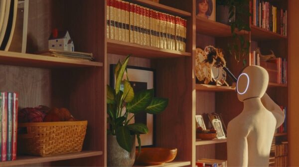 Робот с светящимся лицом стоит у деревянных полок с книгами в уютной комнате.
