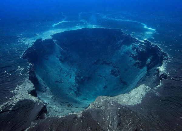 Подводный кратер в океане, окружённый каменистой поверхностью и глубокими водами.