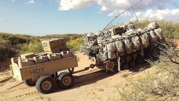 Беспилотная военная техника в пустыне с грузом и оборудованием.