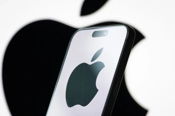 Смартфон с логотипом Apple на экране, на фоне большого логотипа компании.