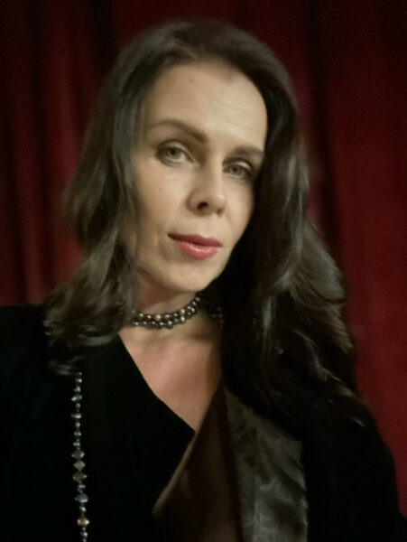 Кто ты: архитектор будущего или гармоничный симбионт? 5 Человек в вечернем наряде и украшениях на фоне красного занавеса.