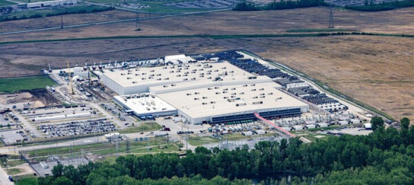 Завод с белой крышей среди полей и деревьев, аэрофотосъёмка.