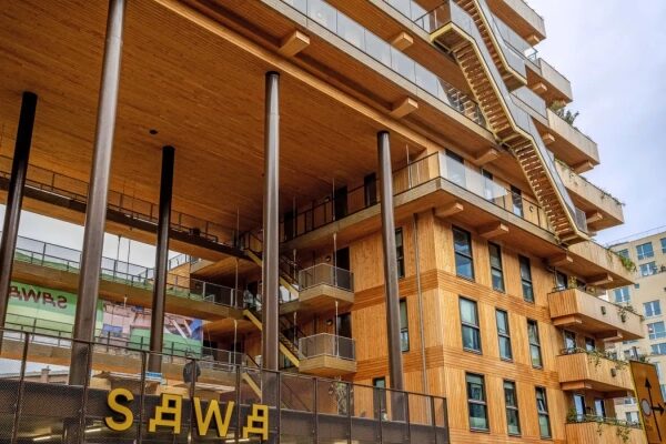 Многоэтажное деревянное здание в современном стиле с террасами и внешними лестницами.