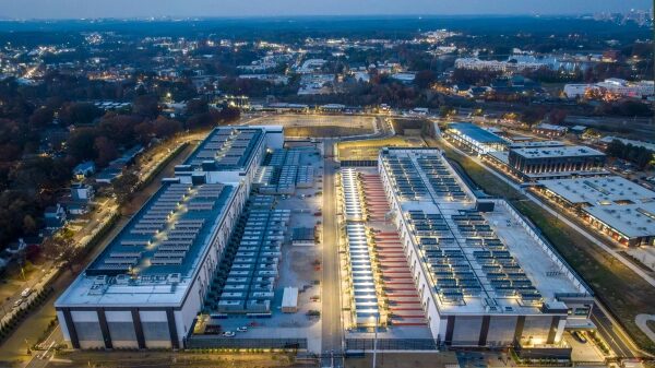 Центр обработки данных ночью, панорамный вид сверху на освещенные здания и город.