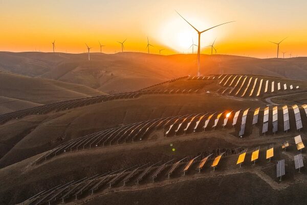 Солнечные панели и ветряки на холмах при закате, возобновляемая энергия.