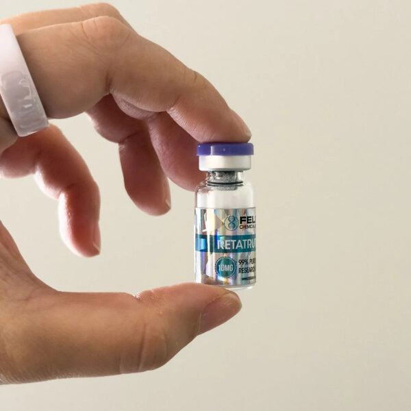 Рука держит маленький медицинский флакон с препаратом на белом фоне.