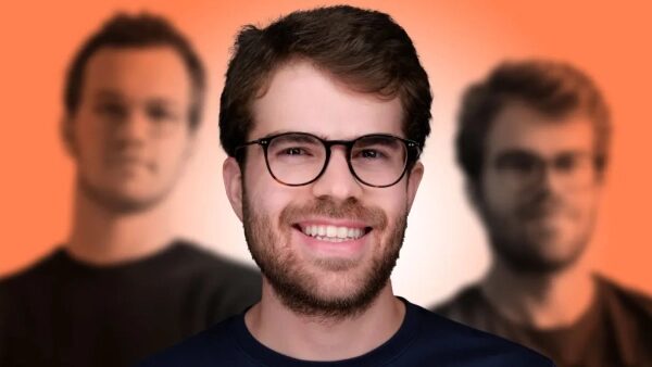 Молодой мужчина в очках с улыбкой на фоне размытых фигур на оранжевом фоне.