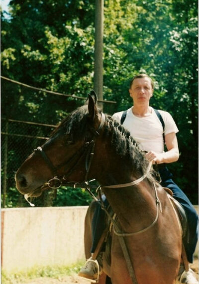 Человек верхом на лошаде на открытом воздухе, летний день, зелёный фон.