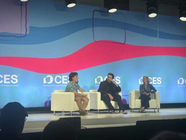 Три человека на сцене на конференции CES, обсуждают технологии.