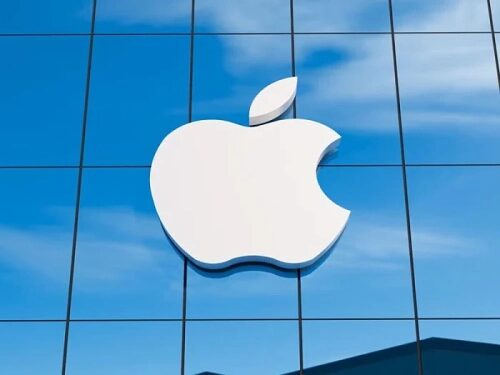 Логотип Apple на стеклянной стене, отражающий голубое небо.