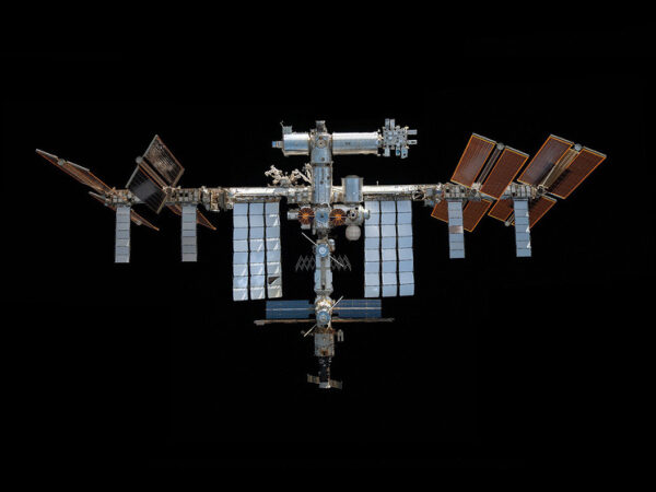 Международная космическая станция на орбите с солнечными панелями на фоне космоса.