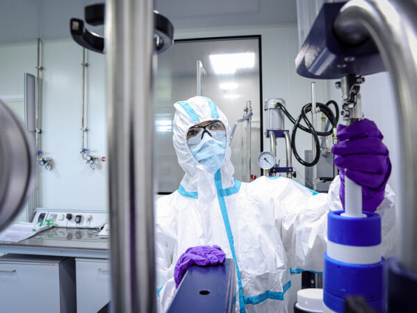 Учёный в защитном костюме работает в лаборатории.
