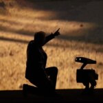 Человек и робот против пустынного фона в драматическом освещении.