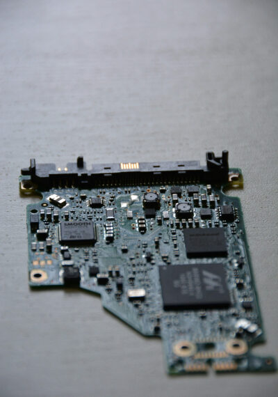 Печатная плата с чипами и коннекторами на сером фоне, вид сверху.