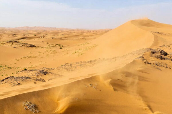 ДНК отличается от современных людей: Археологи обнаружили загадочные мумии возрастом 7 тысяч лет 3 Песчаные дюны в пустыне под синеватым небом, легкий ветер создает мерцающие узоры.