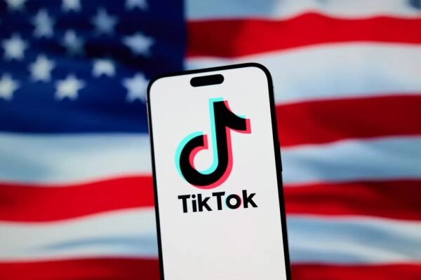 Смартфон с логотипом TikTok на фоне флага США.