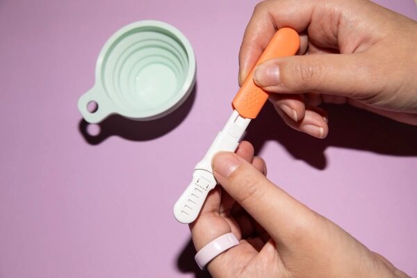 Человек держит в руках прибор для тестирования Ultra4 Wand, на заднем плане видна складная чашка светло-мятного цвета.