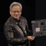 Человек в кожаной куртке демонстрирует компьютерную плату.