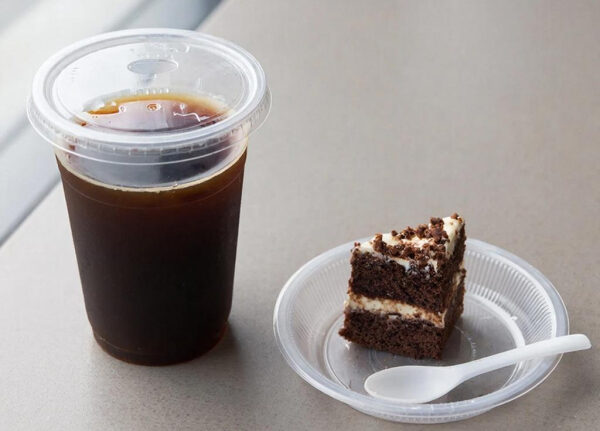 Стакан кофе с крышкой и кусочек шоколадного торта на тарелке.