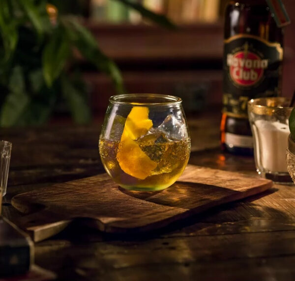 Коктейль с бокалом и ромом на деревянной доске, фонарь Havana Club сзади.