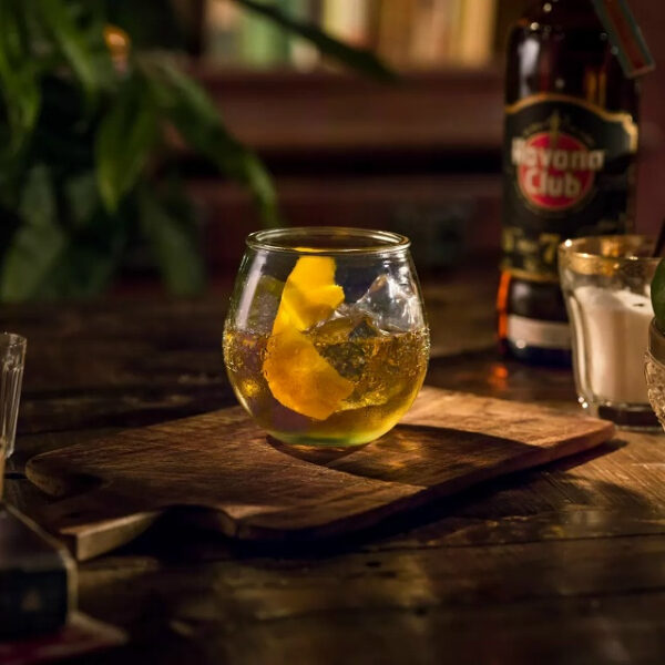 Коктейль с бокалом и ромом на деревянной доске, фонарь Havana Club сзади.