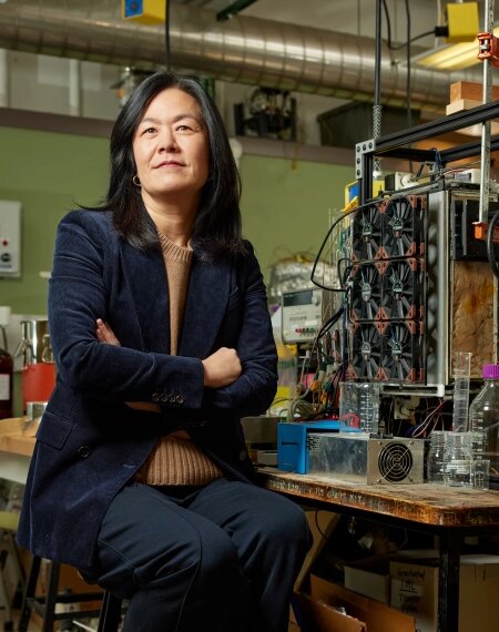 Женщина в научной лаборатории сидит перед экспериментальным оборудованием.