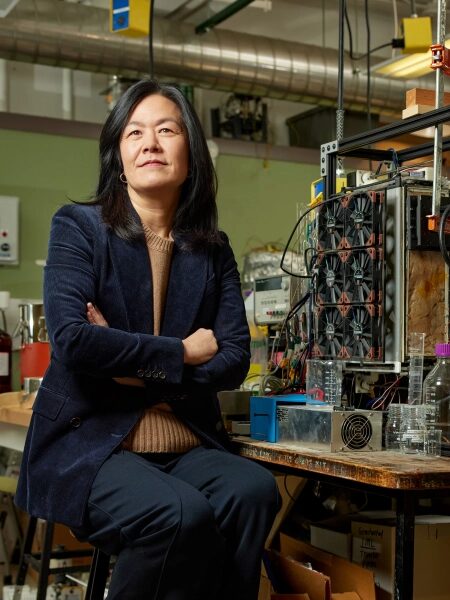 Женщина в научной лаборатории сидит перед экспериментальным оборудованием.