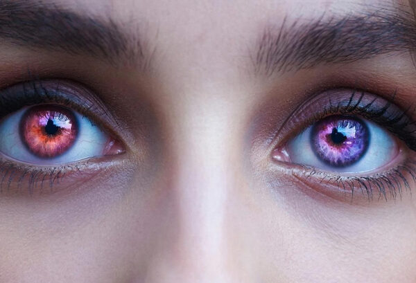 Крупный план глаз с ярким макияжем, подчеркнутым синими тенями и длинными ресницами.