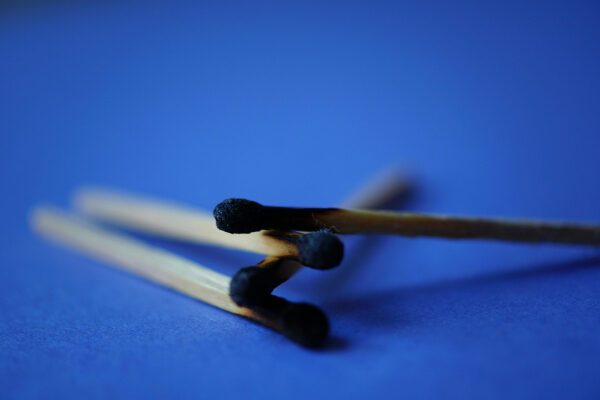 Сгоревшие спички на синем фоне, крупный план.
