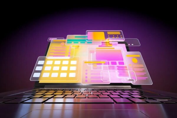 Ноутбук с яркими разноцветными голограммами интерфейсов на темном фоне.