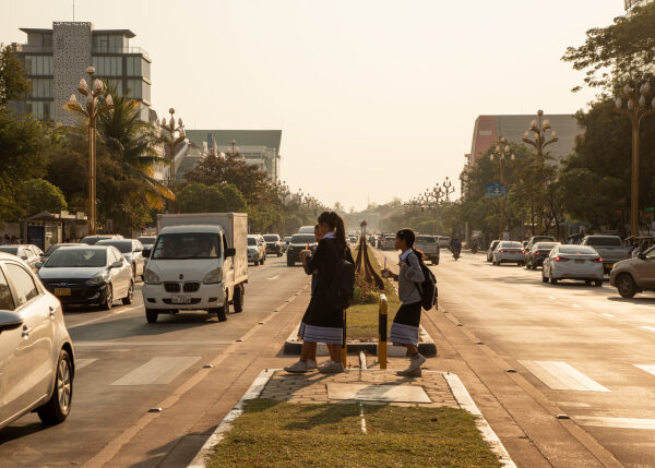 Люди пересекают многополосную городскую улицу на пешеходном переходе.