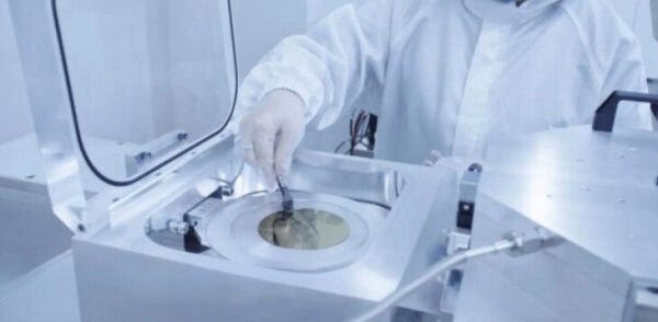 Человек в защитной одежде работает с полупроводниковым оборудованием в лаборатории.