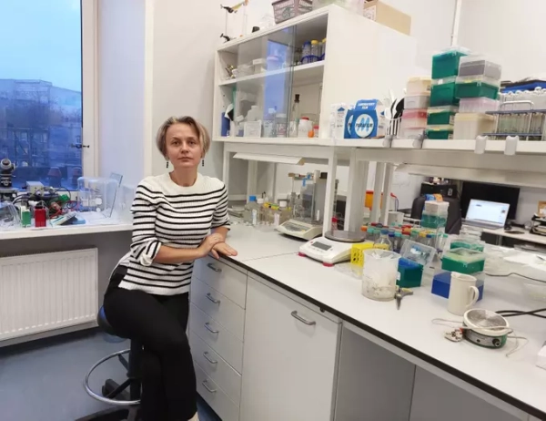 Женщина в лаборатории, окружённой научным оборудованием и материалами для экспериментов.