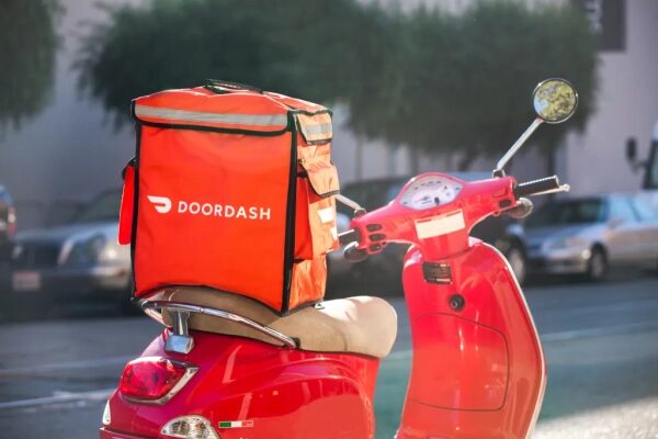Красный скутер с сумкой DoorDash на улице города.