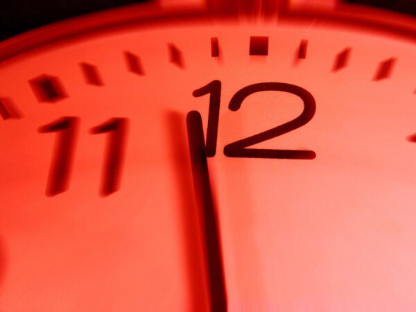 Часы крупным планом, показывающие время около полуночи, с красным фоном.