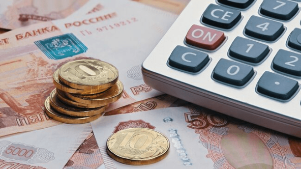 Калькулятор и российские рубли: монеты и купюры на столе, финансовый подсчет.