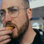 Мужчина на фоне причала и здания с колоннами летом.